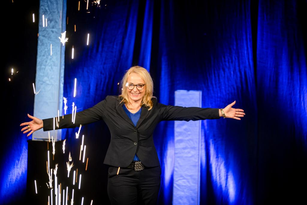 Ein packendes Keynote-Speaking Event. Simone Zahn auf einer Bühne mit blauem Hintergrund.